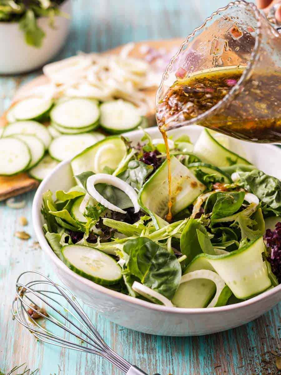 pouring blackcurrant vinaigrette onto a salad