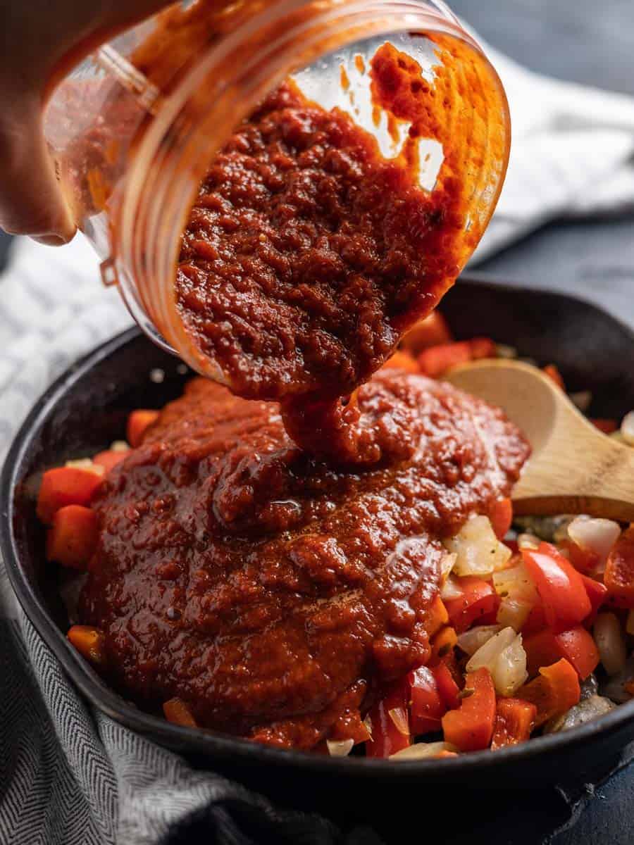 pouring adobo into a castiron pan