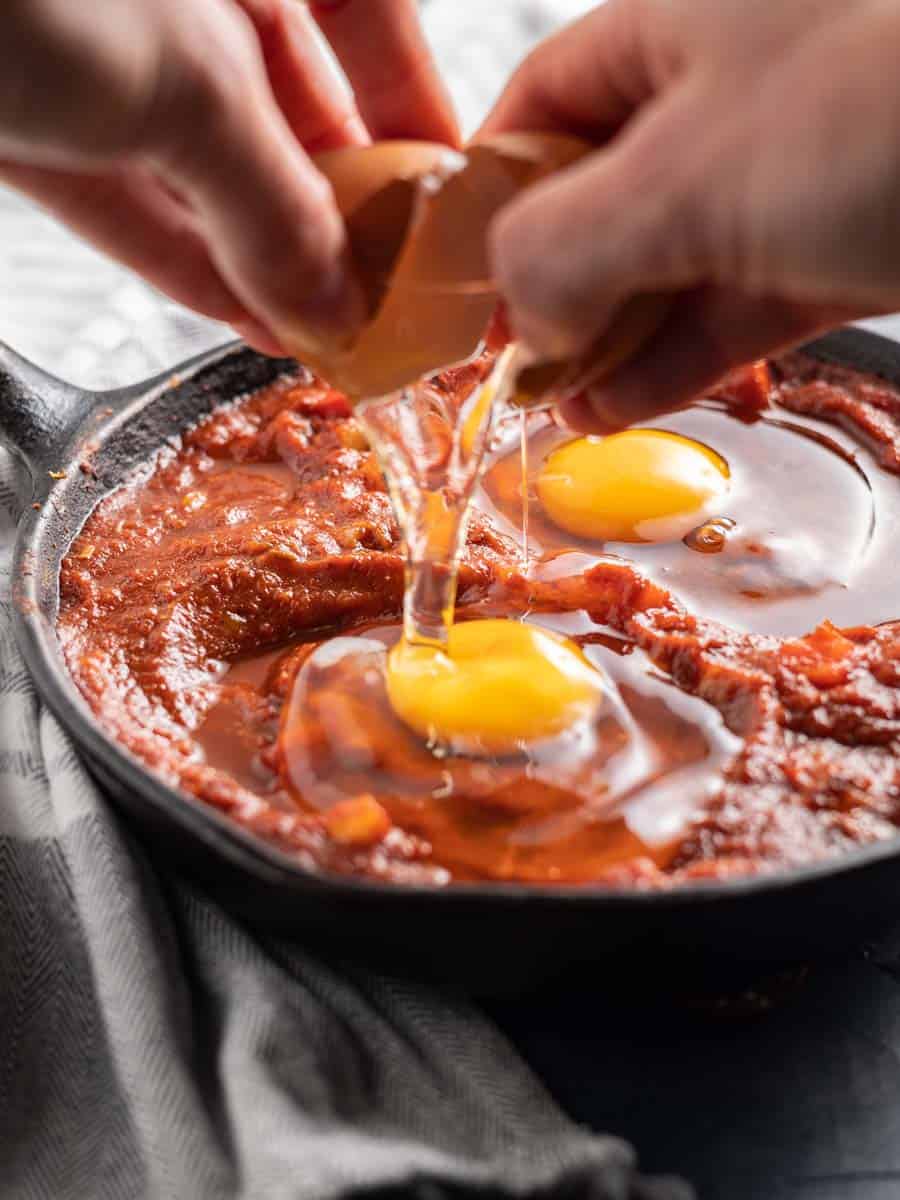breaking eggs into the castiron pan filled