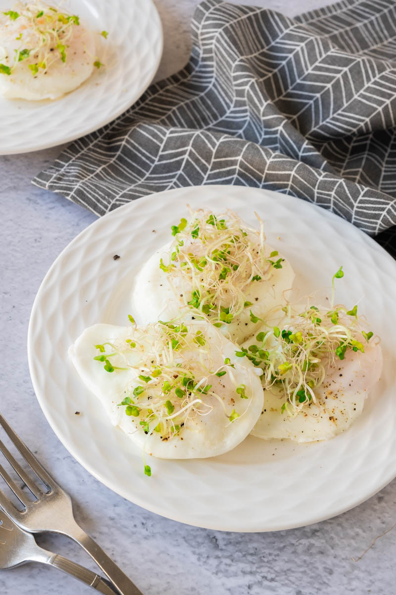 Poached eggs on plate with watercress on top.