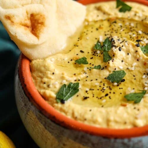 scooping vadouvan hummus onto pita bread