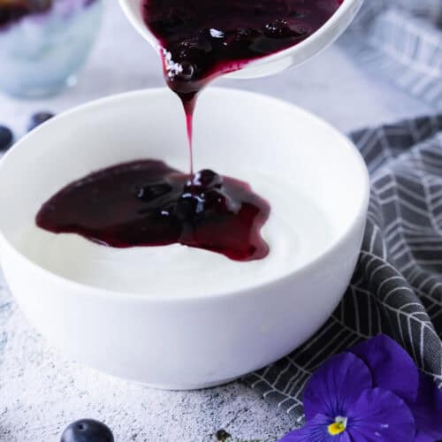 Blueberry compote poured over yogurt.