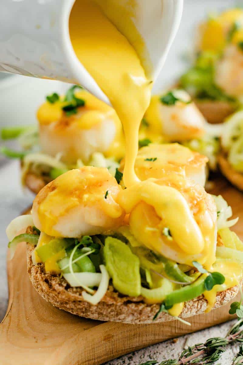 pouring hollandaise on scallop benedict