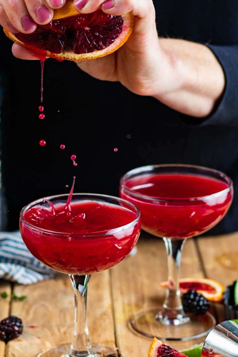 squeezing blood orange in cocktail glass