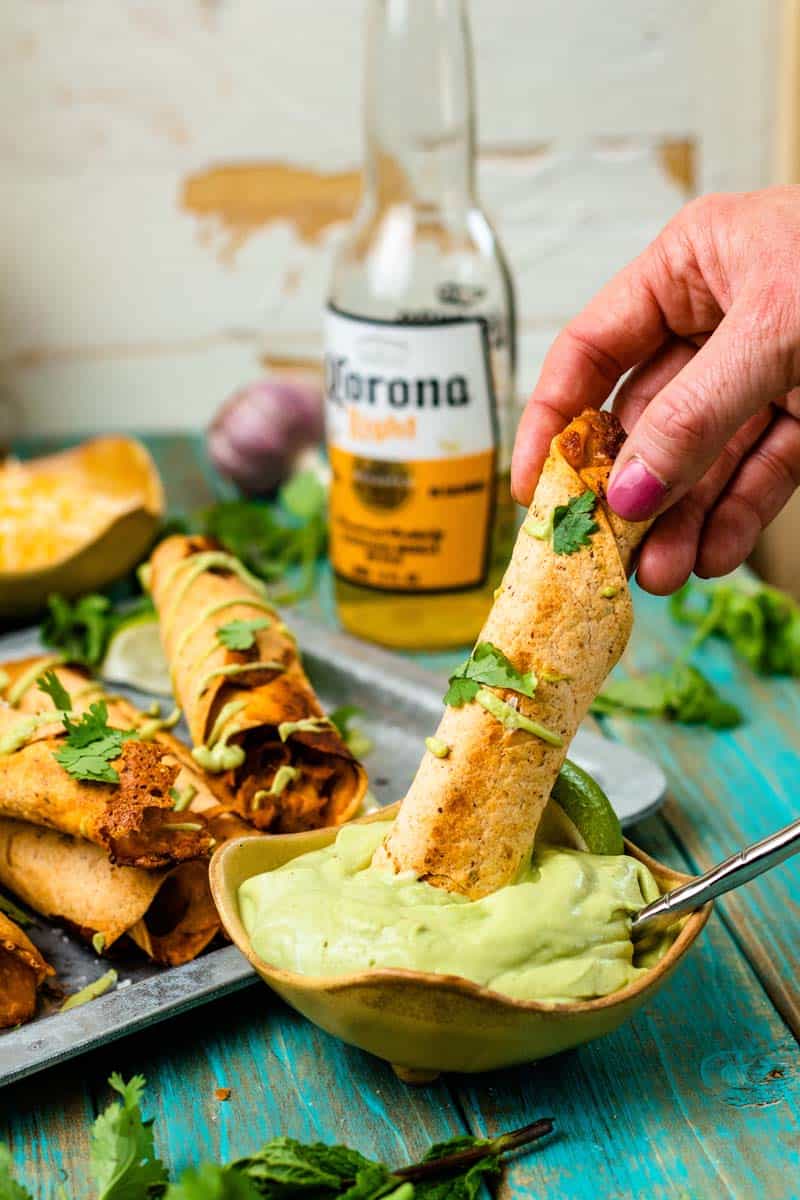 Chicken tinga taquitos dipped in avocado crema