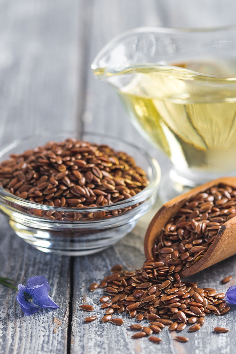 Flaxseed oil in a glass jar, surrounded by flaxseeds.