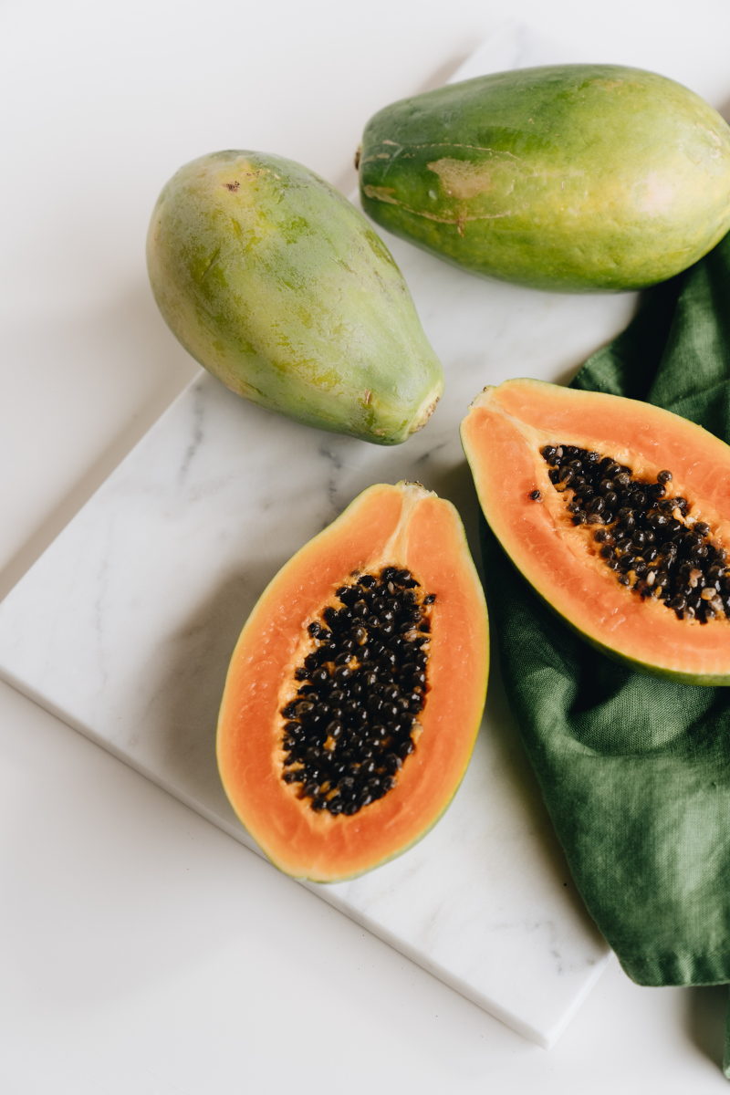whole and cut papayas on on a white background.
