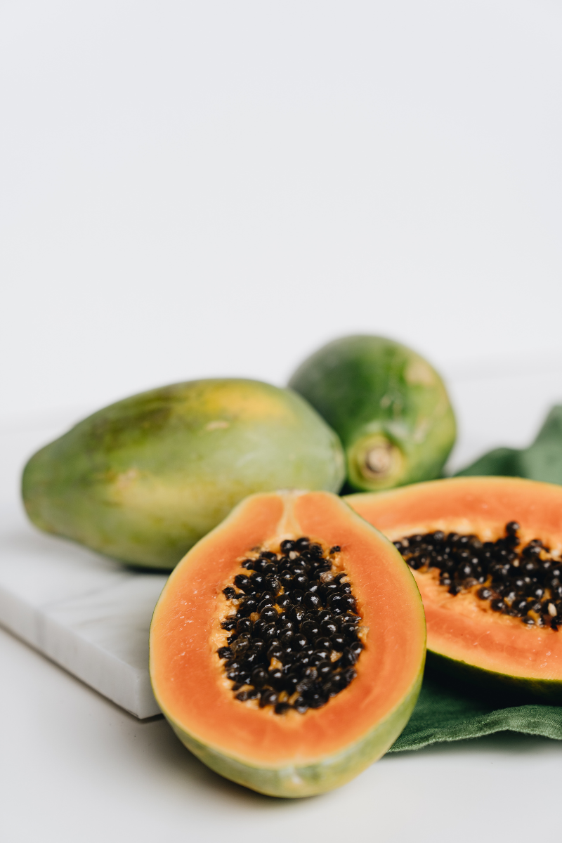 whole and cut papayas on on a white background.