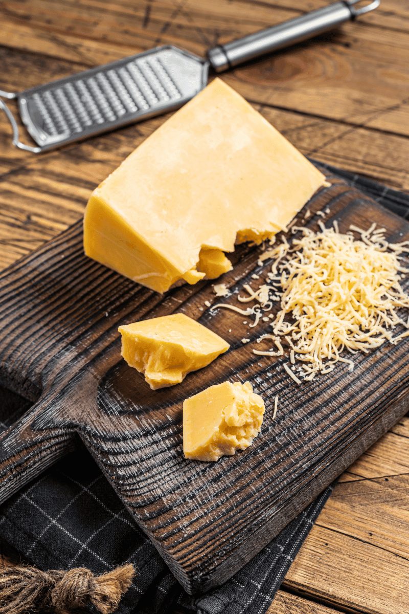 Cheddar cheese and hand grater on a towel.