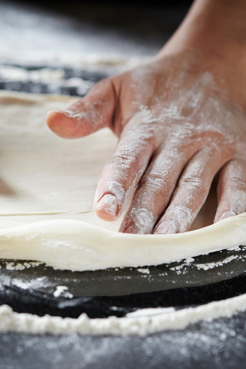 Pizza dough on a dark surface.