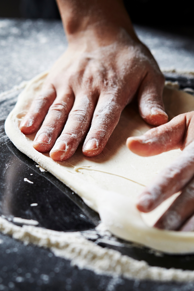 Pizza dough on a dark surface.