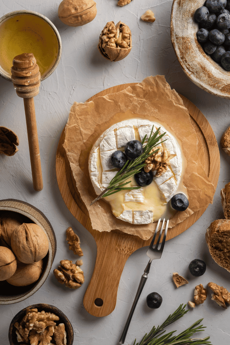 Baked camembert on paper and wooden cutting board.