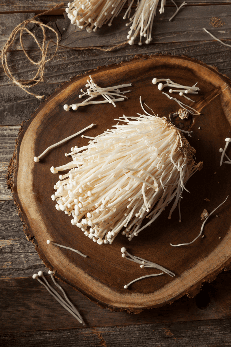 Enoki mushrooms on a wooden block.