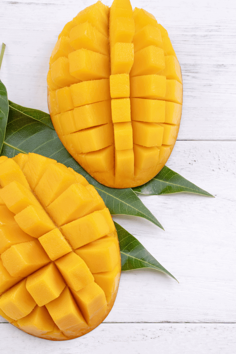 Cut mangoes on a wooden surface.