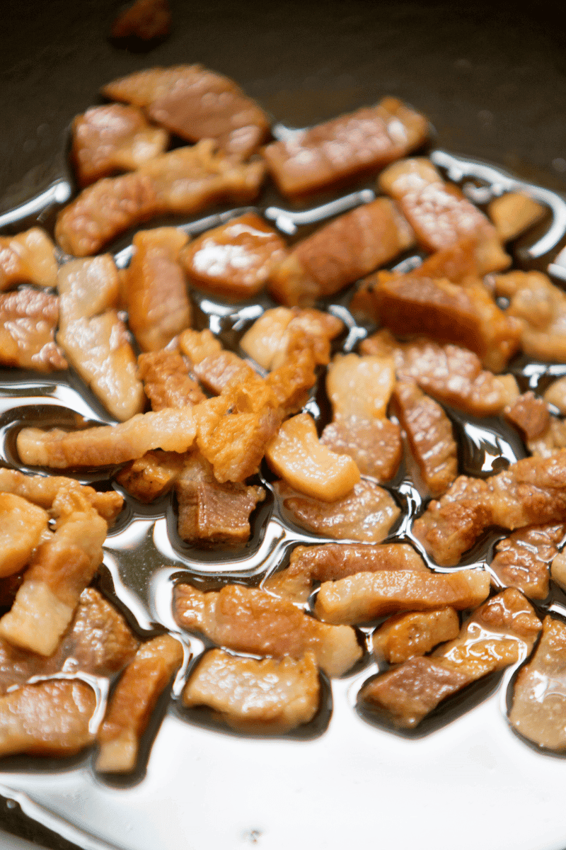 Guanciale sizzling in a fry pan.