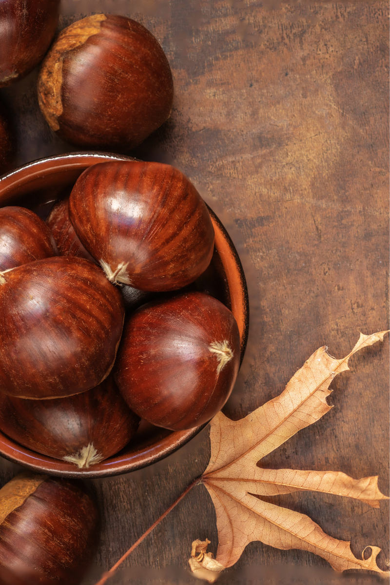 chestnuts in a bowl, on a wooden surface.