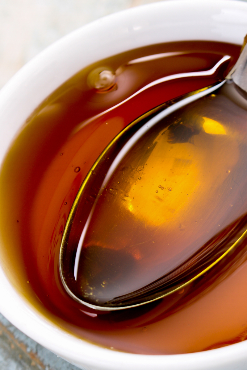 Golden syrup in a bowl and on a spoon.