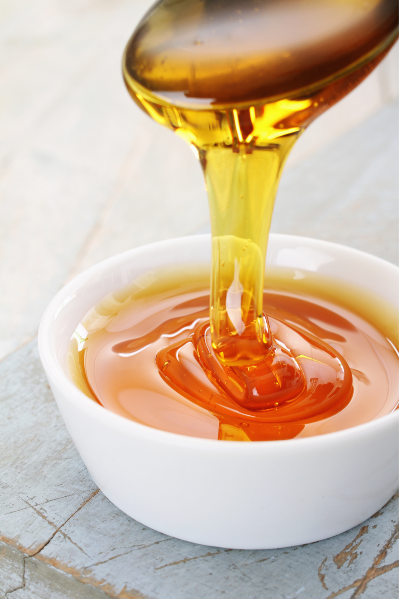 Golden syrup in a bowl and on a spoon.