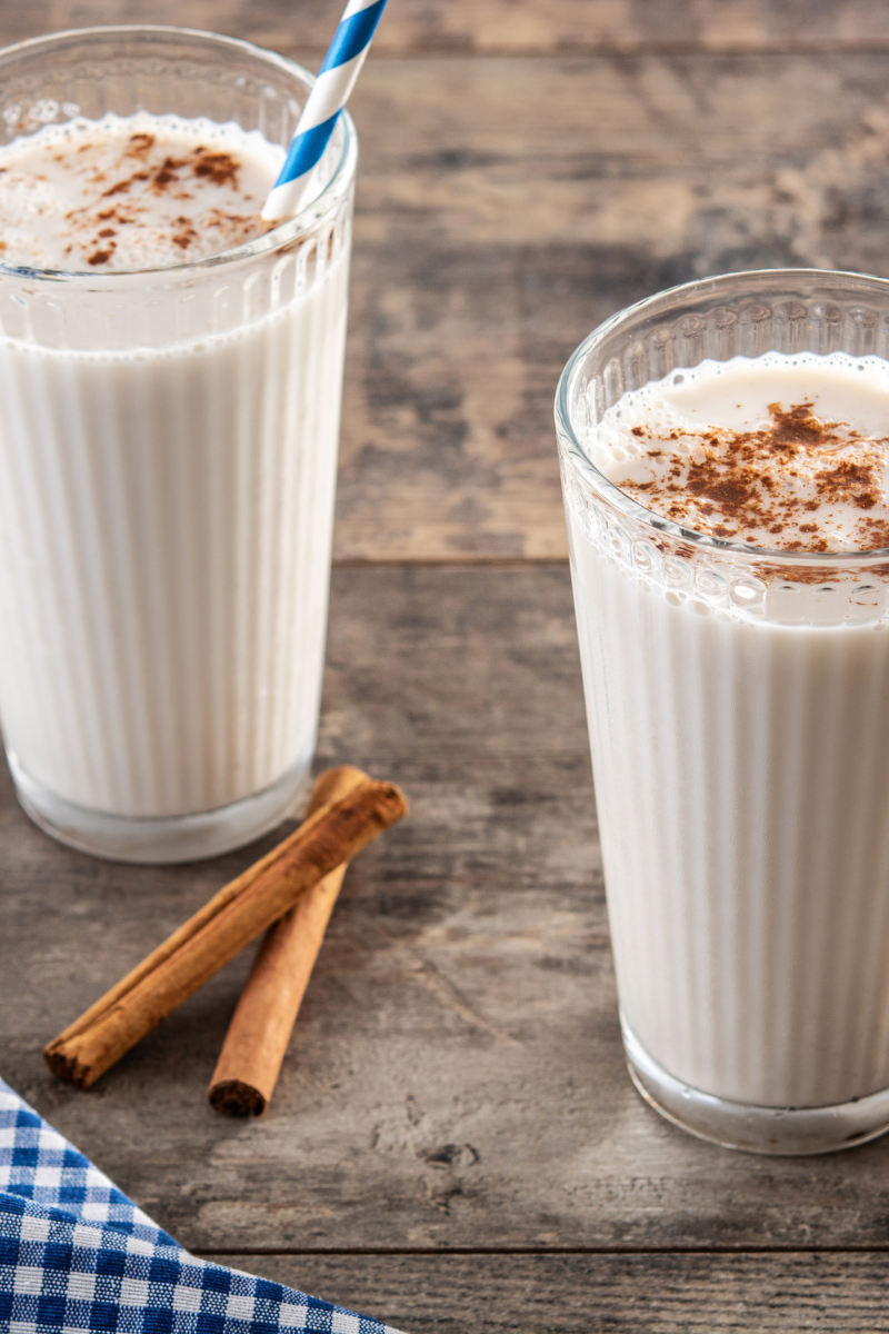 Horchata in tall glasses on a wood surface.