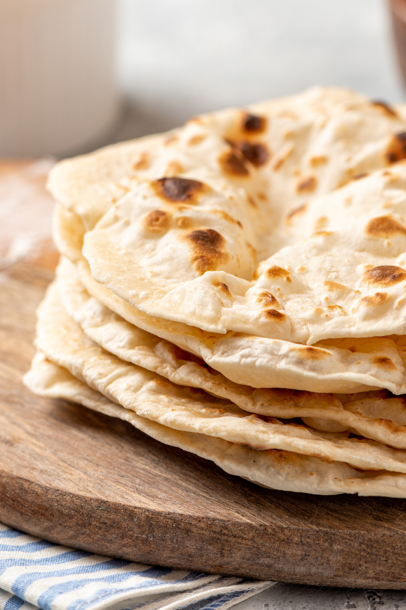 Roti flatbread stacked on a cutting board.