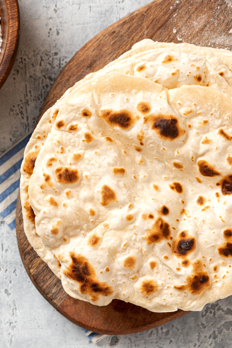 Roti flatbread stacked on a cutting board.