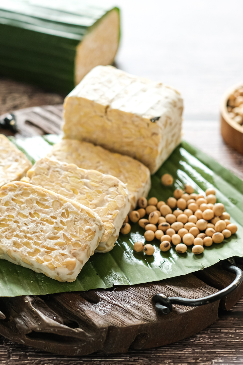tempeh sliced and whole, on a leaf.